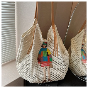 Close-up of cream knit tote bag with colorful girl embroidery and leather tassel strap