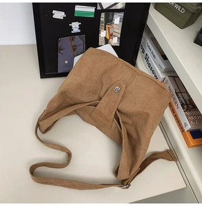 Detail of camel canvas crossbody bag with vintage metal button and adjustable strap
