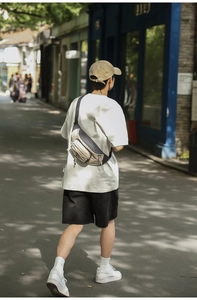 Rear view of model wearing a two-tone beige and grey nylon crossbody chest bag outdoors