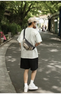 Close-up of a beige and black nylon crossbody bag with multi-zipper compartments