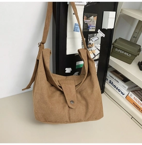 Detail of a brown canvas hobo bag featuring a retro round metal buckle and wide strap