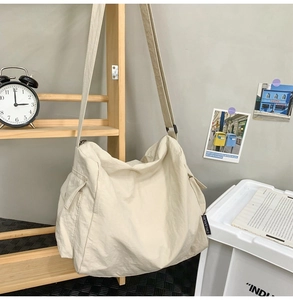 Vue détaillée du sac fourre-tout en toile crème avec bandoulière large et poche