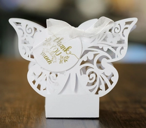 Close-up of white laser-cut butterfly gift box with silk ribbon and thank you tag