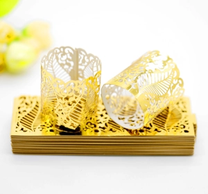 Detailed macro view of laser-cut gold hollow paper tea light wraps with leaf patterns