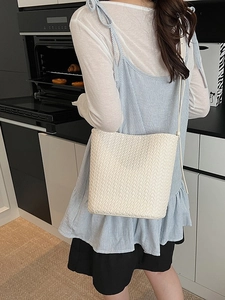 Chic cream woven bucket bag for women featuring a minimalist crossbody strap design