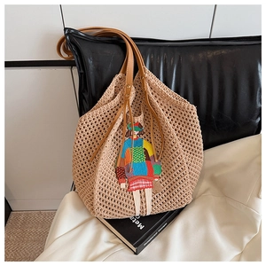 Detail of beige knit tote bag featuring a colorful cartoon girl embroidery and brown leather straps