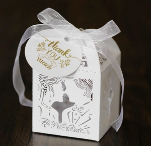 Close-up of laser-cut wedding favor box with silhouette design and thank you tag