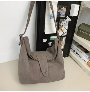 Detail of taupe canvas crossbody bag with metal buckle in a minimalist artistic setting