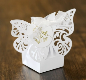 Detail of white laser-cut hollow butterfly gift box with ribbon and thank you tag
