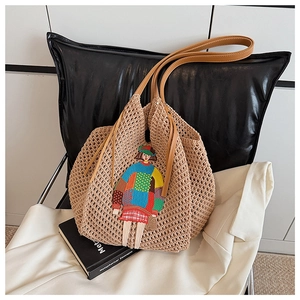 Close-up of knit tote bag with colorful girl embroidery and leather shoulder straps