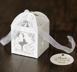 Detail of white laser-cut wedding favor box with silhouette and thank you tag