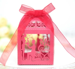 Macro view of red laser-cut wedding favor box featuring Mr & Mrs proposal cutout