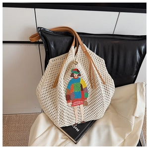 Close-up of beige crochet tote bag featuring colorful girl embroidery and leather handles