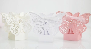 Laser-cut butterfly wedding favor boxes with ribbons in cream, white, and pink finishes