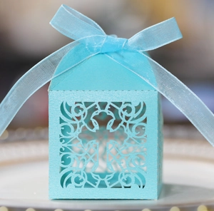 Close-up of light blue laser-cut cross gift box with elegant silk ribbon bow detail