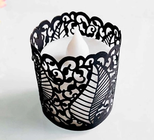 Detail of laser-cut black hollow leaf pattern paper cover for LED tea light candles