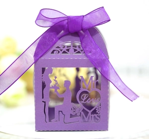 Detail of purple laser-cut wedding favor box with ribbon bow and romantic cutout patterns