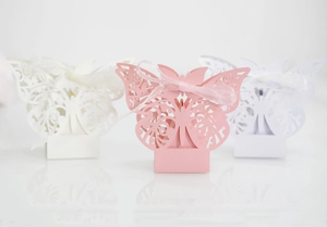 Detail of laser-cut hollow butterfly candy boxes with elegant ribbons for wedding favors