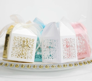 Close-up of laser-cut cross patterns on elegant paper candy boxes with ribbon bows