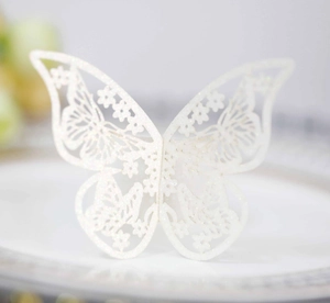 Primer plano de servilletero de mariposa blanca cortada con láser y detalles florales finos