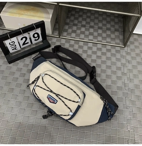 Close-up of beige and navy crossbody bag with bungee cord detail and adjustable strap