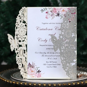Detail of laser-cut butterfly wedding invitation with silver glitter and rose floral insert