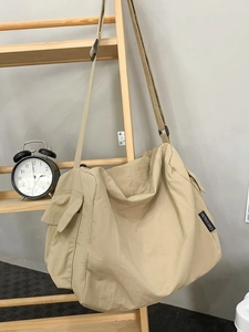 Grand sac cabas en toile kaki avec poche latérale suspendu sur un support en bois