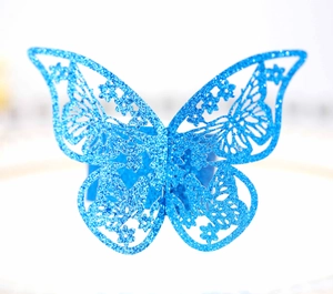 Detalle de un servilletero de mariposa azul con purpurina y patrones florales calados