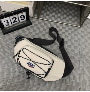 Close-up of cream crossbody bag with black cords and adjustable strap details