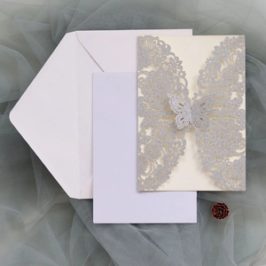 Detail of silver glitter laser-cut butterfly invitation with cream card and white envelope