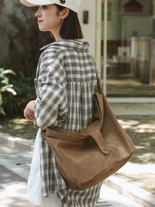Brown large capacity canvas crossbody bag with metal buckle shown on a female model