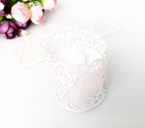 Macro shot of white laser-cut hollow paper candle shade with elegant feather patterns