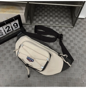 Close-up of contrast crossbody bag with elastic cord detail and woven logo strap