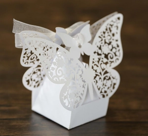 Macro detail of laser-cut white butterfly wedding favor box with delicate floral patterns