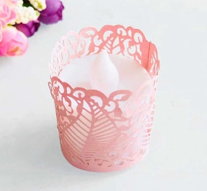 Macro view of pink laser-cut hollow paper tea light wrap with LED candle