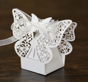 Detailed laser-cut white butterfly candy box with elegant floral patterns and a ribbon