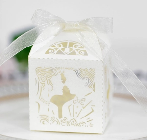 Detalle de caja de dulces para boda marfil troquelada con silueta de novios y lazo