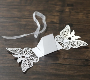 Detailed laser-cut butterfly gift box with floral patterns and white ribbon on wood