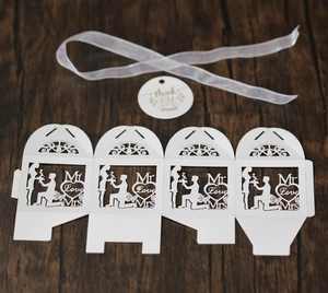Flat lay of laser-cut white wedding favor box with Mr & Mrs silhouette and gift tag