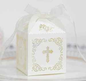 Vue macro d'une boîte à dragées croix découpée au laser avec ruban en organza blanc