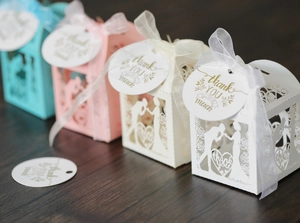 Detail of laser-cut wedding favors boxes with heart tags and decorative ribbons