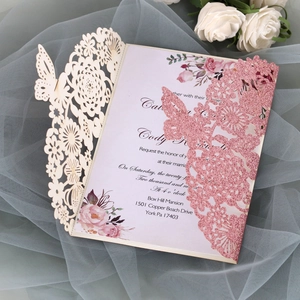 Macro shot of glittery pink butterfly cutout wedding invitation with floral lace patterns