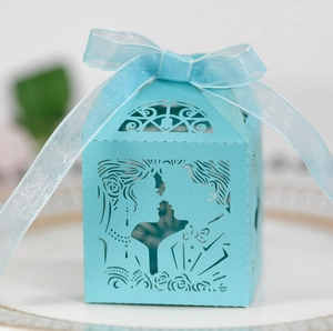 Primer plano de caja de dulces azul claro con corte láser, silueta nupcial y lazo