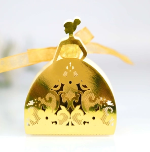 Macro shot of gold hollow-out laser cut girl favor box with metallic finish and gold ribbon