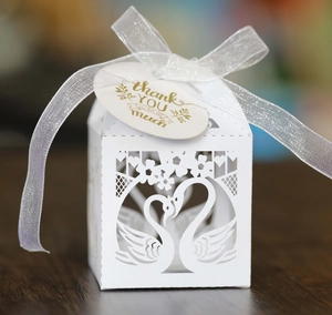 Detail of white laser-cut swan heart candy box with ribbon and thank you tag