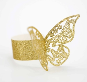 Detalle de servilleteros de mariposa con purpurina dorada cortados con láser para eventos
