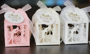 Detail of laser-cut wedding favor boxes with heart patterns, silk ribbons, and tags