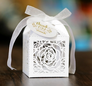 Detail of laser-cut rose hollow favor box with white ribbon and thank you tag