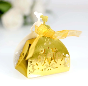 Detail of laser-cut gold wedding favor box featuring intricate floral lace and yellow ribbon