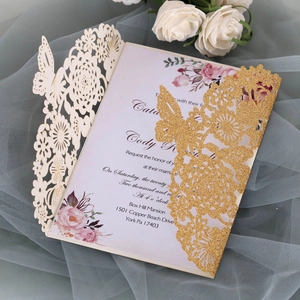 Macro detail of laser-cut butterfly wedding invitation with glitter gold and floral inserts